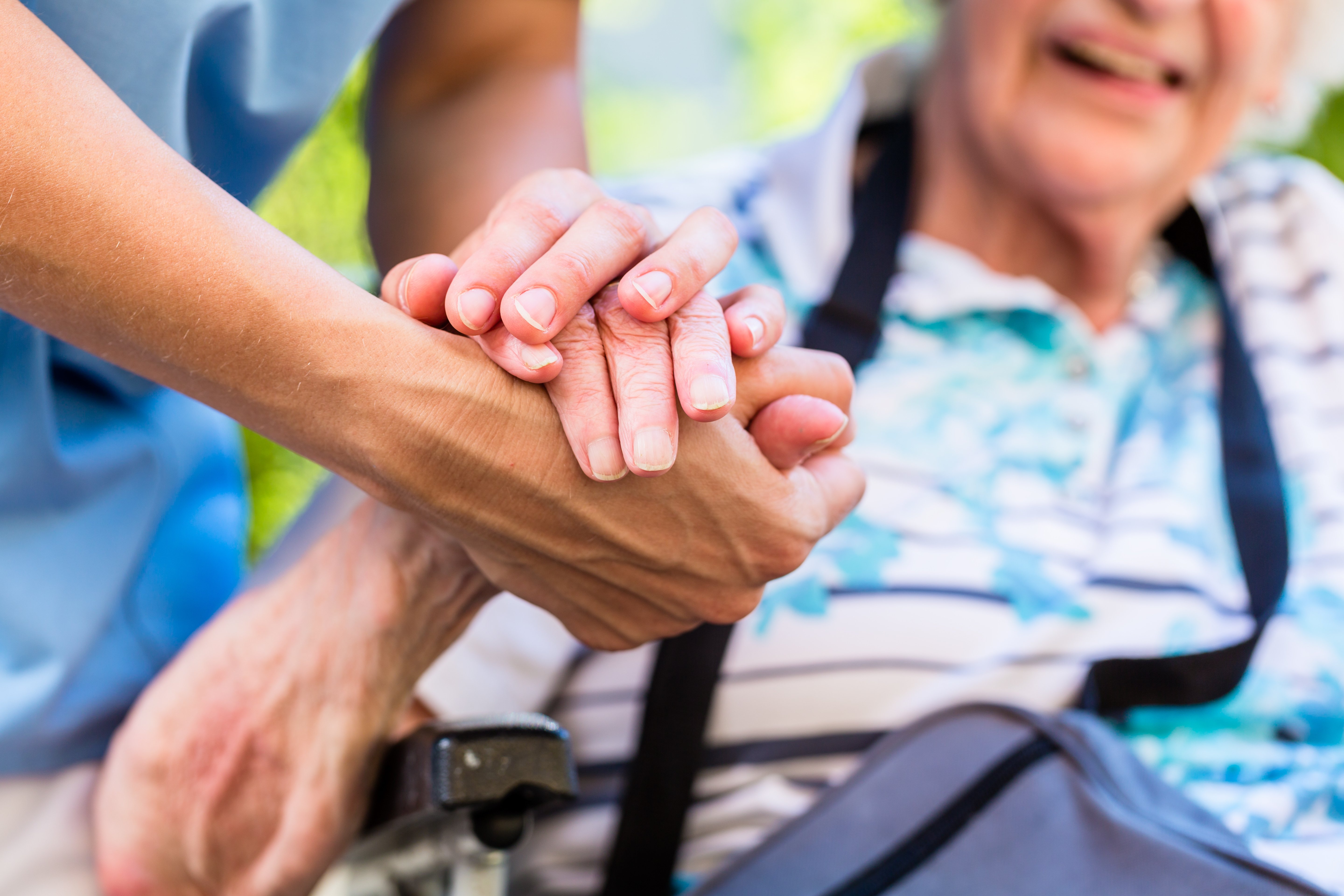 Close up shot of a person holding an older persons hand